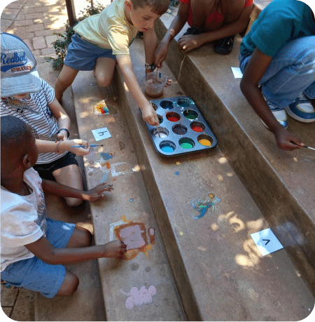 A group of young children doing brain-friendly exercises, including painting, to spark creativity